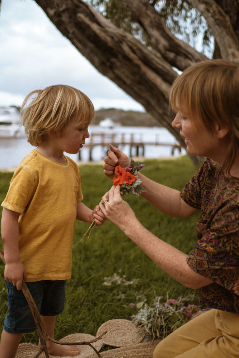 Mother pointing out a snail on a little bouquet of flowers to her son. An orange nasturtium in=s the main flower.