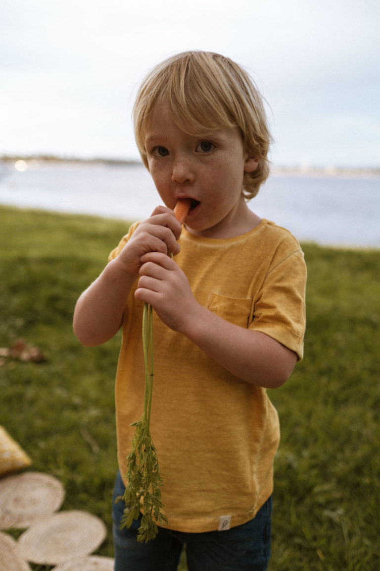 Young boy eating a raw carrot outdoors