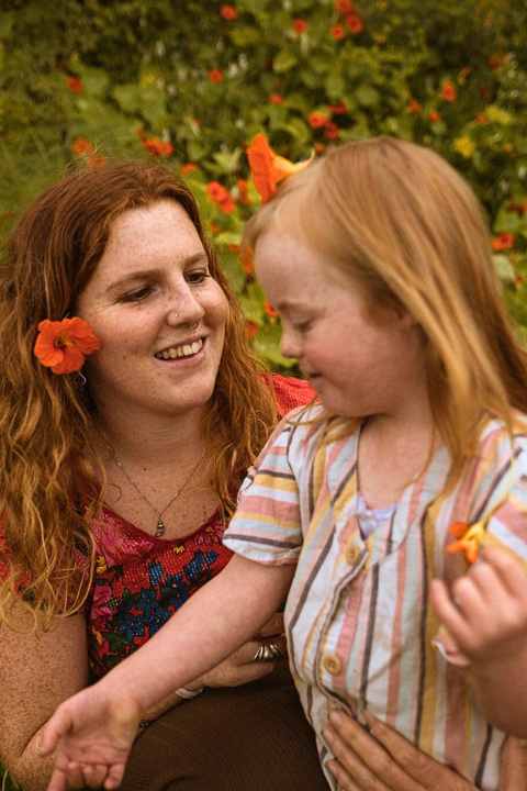A young woman about 17 with a young girl of 6 who has Down's syndrome, in a field of nasturtiums