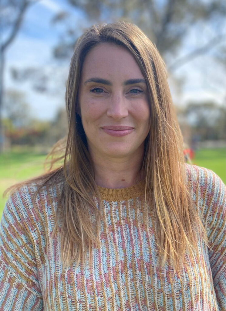 Mid thirty year old woman. Close up smiling, long hair wearing a jumper