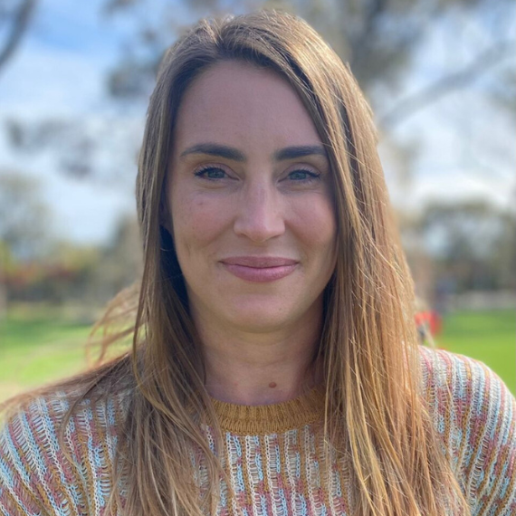 Mid thirty year old woman. Close up smiling, long hair wearing a jumper